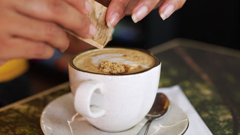 woman putting brown sugar on coffee