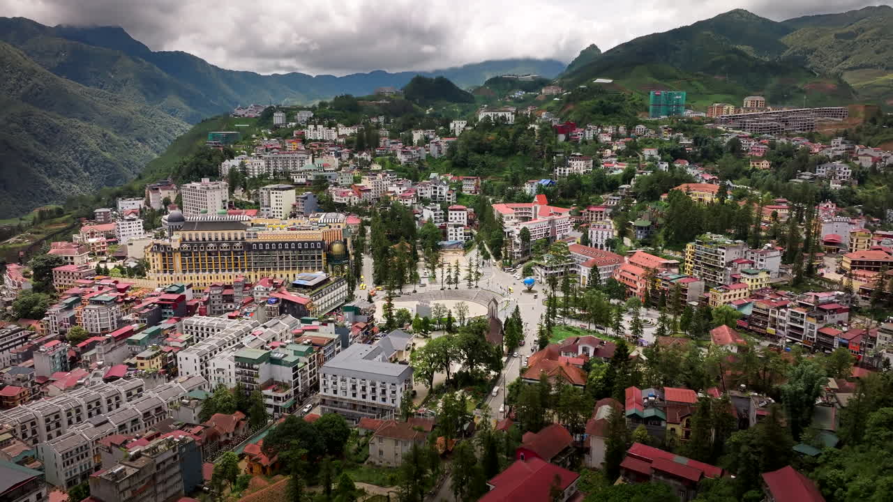 Sa Pa town buildings and street view surrounded by lush green mountain landscape, Establishing drone shot