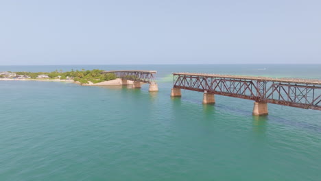 aerial dolly to broken bridge with large section missing, disconnect between sandy island and mainland