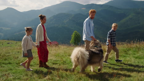 happy family walk dog on beautiful mountain slope. father walking pet with son