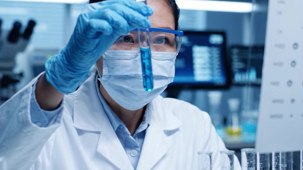 A dedicated scientist meticulously conducts laboratory experiments, showcasing precision in handling test tubes and vials while wearing protective gear in a high-tech environment.