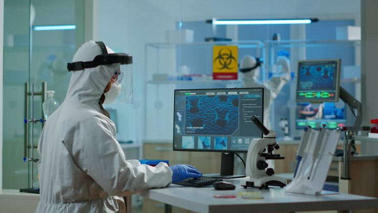 Medical scientist in ppe suit working with DNA scan image typing on pc
