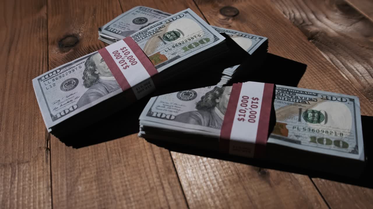 Three Stacks of 10000 American Dollars Banknotes in Bundles Lie on Wooden Table