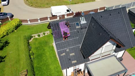 aerial view of roofers installing solar panels on a house, showcasing sustainable energy solutions and home improvement