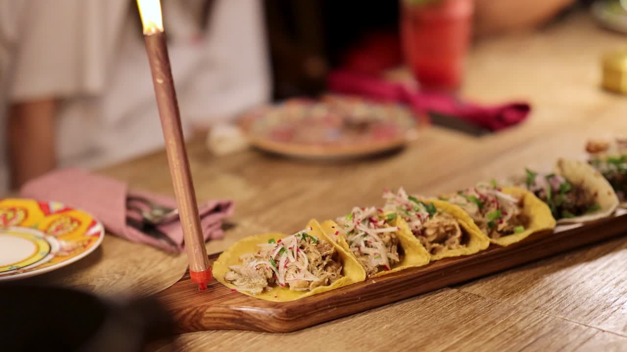 A colorful array of tacos on a wooden table in a warmly lit Mexican restaurant setting