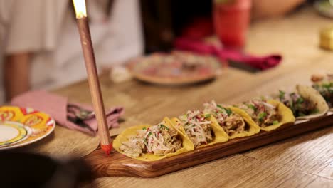 a colorful array of tacos on a wooden table in a warmly lit mexican restaurant setting