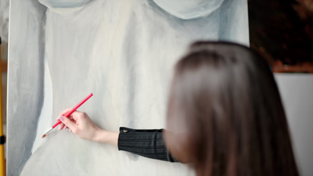Woman painting a female body on a canvas at an art gallery workshop