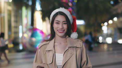 woman wearing a santa hat in a city at night