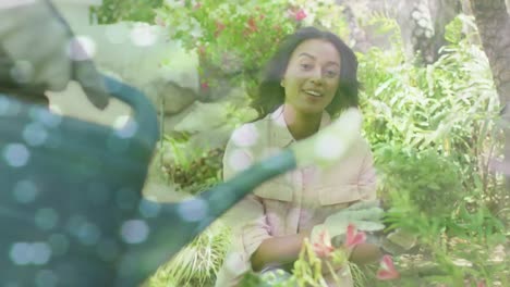 animation of glowing spots over happy biracial couple with watering can gardening