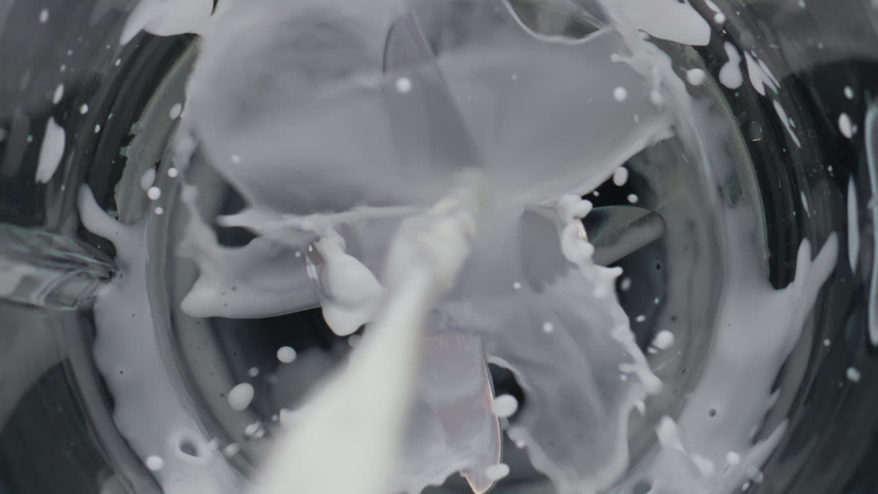 Milk pouring empty blender close up. Top view dairy product adding in mixer.