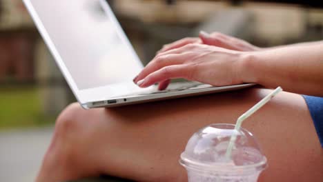 mujer escribiendo en una computadora portátil al aire libre