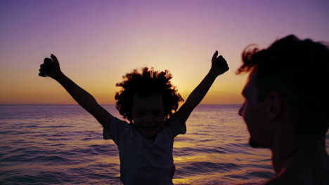 father and son enjoying a joyful moment silhouetted against a beautiful sunset at the beach