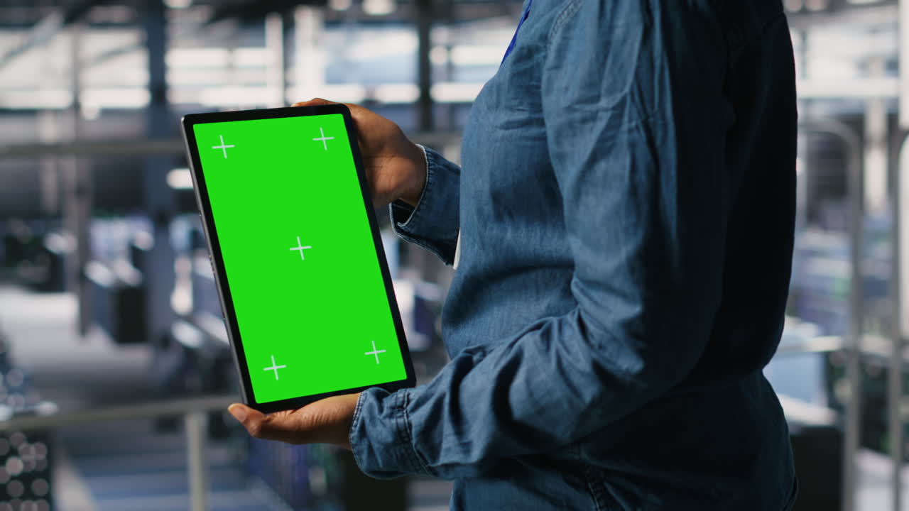Data center worker using green screen mockup tablet, doing maintenance, closeup