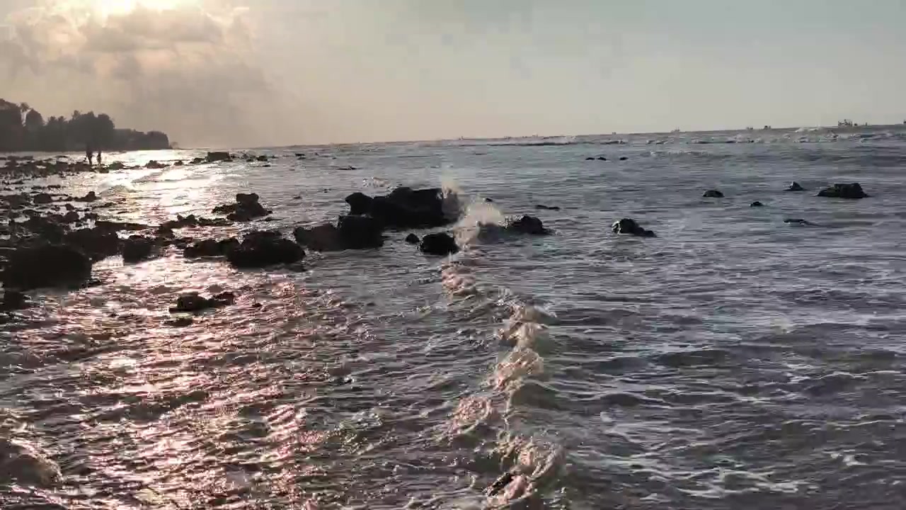 Onde dell'oceano che si infrangono su spiaggia rocciosa al tramonto