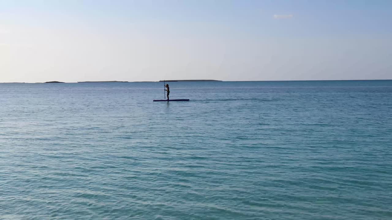 젊은 백인 소년은 바하마의 바다에서 패들보드를 사용합니다.