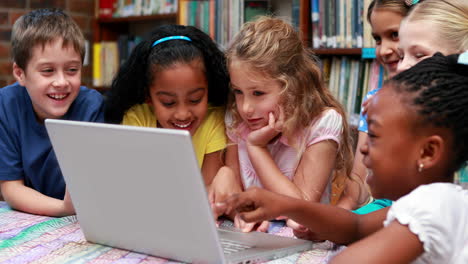 alumnos que usan el portátil juntos en la biblioteca