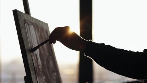 fully concentrated sophisticated female artist in her 20's is drawing picture on easel. slow motion close up footage