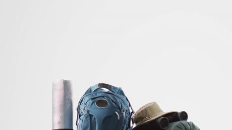 camping equipment with rucksack and hat and copy space on white background