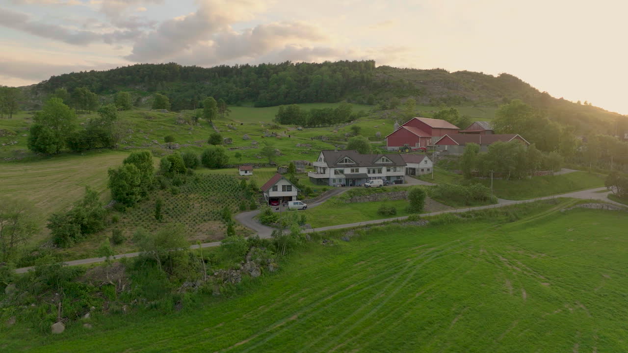 Kylän taloja vehreiden niittyjen ja metsäisten kukkuloiden ympäröimänä auringonlaskun aikaan.