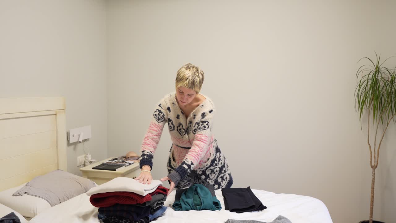 Woman folding clothes in bedroom