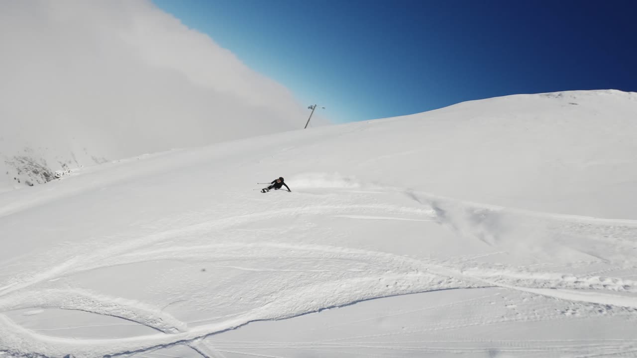 An exhilarating FPV drone shot capturing a snowboarder carving through deep powder snow on a bright winter day. The dynamic perspective highlights the snowboarder in the untouched snowy terrain