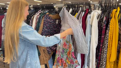 used clothes, vintage fashion at a flea market. side view of young woman shopping in thrift store. a customer in a vintage store. vertical video.