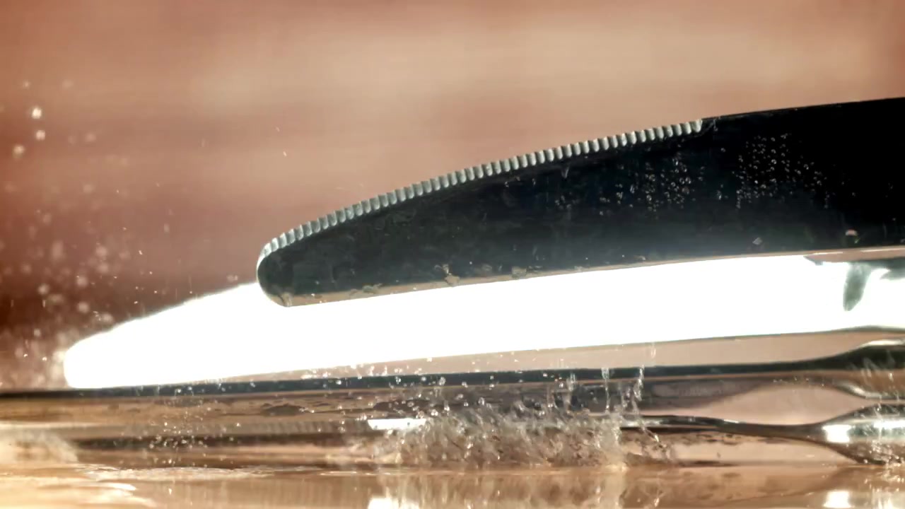 Posate che cadono e schizzano acqua al rallentatore su una superficie di legno
