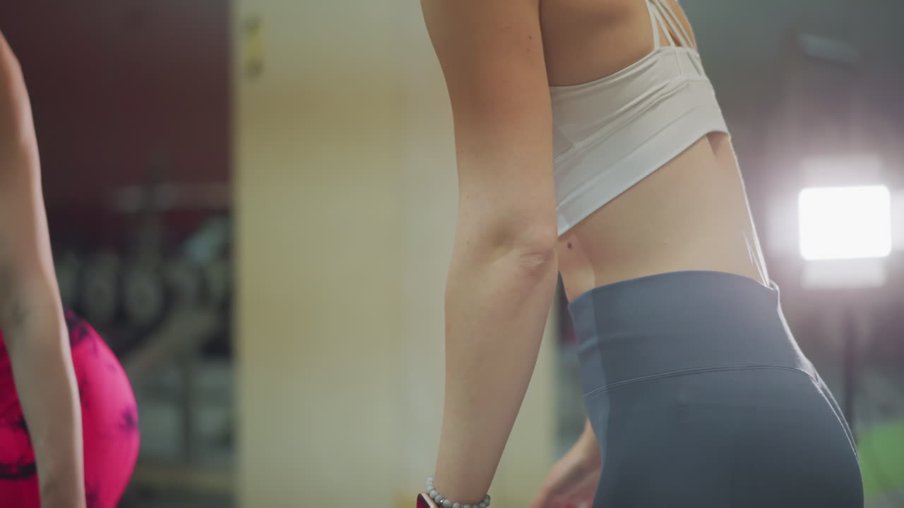 woman adjusting leggings near mirror, performing warmup stretches, checking posture and glute activation under soft studio lights closeup frames reveal bra strap detail, focused preparation, calm