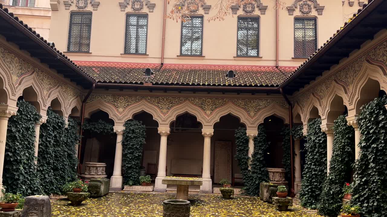 조각된 아치와 무성한 담쟁이 덩굴로 덮인 기둥으로 둘러싸인 평화로운 수도원 안뜰