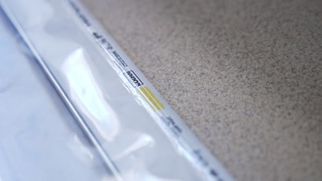metal tool packed into the plastic bag. gloved hand of medic checks the vacuumed bag for integrity. close up.