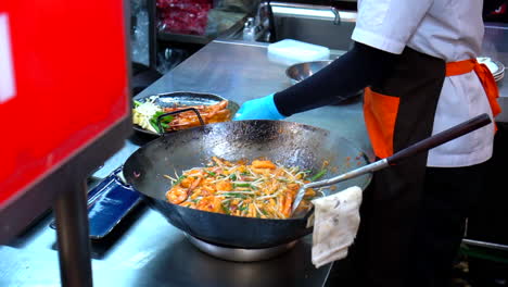 thailand, bangkok - 18 august 2022: seafood pad thai in a hot wok pan ready to be served in thai restaurant
