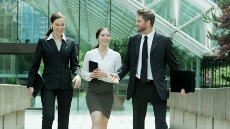 multi ethnic business managers carrying portfolios walking outside