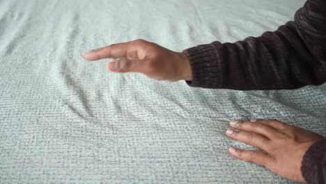 a man's hand is shown touching a patterned fabric with his finger.