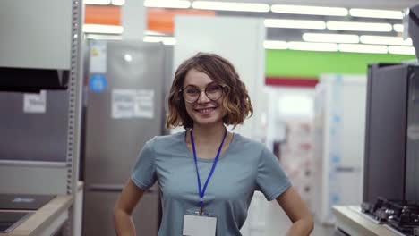 vendedora positiva o retrato de asistente de disparo en una tienda de supermercado. mujer con camisa azul y insignia vacía mirando el