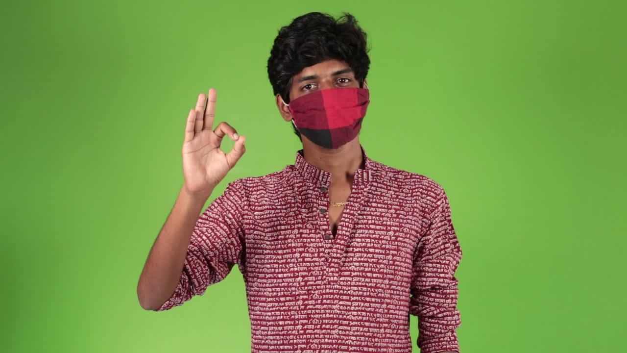 Joyful indian man showing ok sign with fingers with mask . Good-looking Indian man in shirt giving okey sign. Green Chroma Key background.