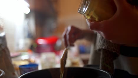 Close-up-of-woman-pouring-honey-in-a-pot,-making-homemade-energy-bars