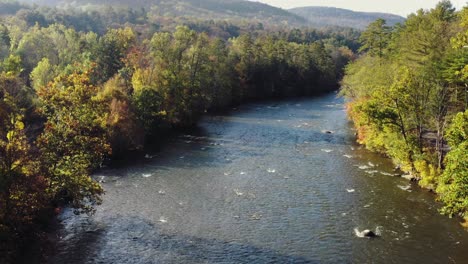 Tiro-Inclinado-Hacia-Arriba-Del-Dron-Del-Río-Housatonic-Que-Pasa-Con-Un-Denso-Bosque-A-Ambos-Lados-En-El-Terreno-Montañoso-En-Litchfield,-Connecticut,-Estados-Unidos-En-Una-Mañana-Soleada