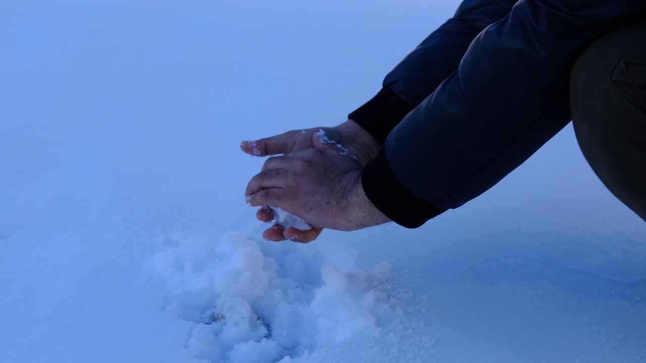 남자가 눈덩이를 만들다