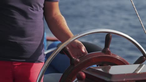 a close up shot of a skipper steering a ship at sea