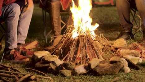 imágenes de mano de un hombre haciendo un fuego de campamento para sus amigos en una noche fría