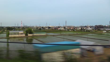 Der-Blick-Auf-Tokio,-Das-Vom-Inneren-Des-Shinkansen-Hochgeschwindigkeitszuges-Mit-Reisfeld-Vorbeifährt