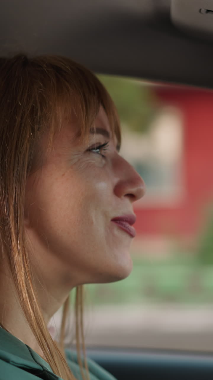 평화로운 여자가 좋아하는 노래를 연주하는 차를 운전합니다. 만족스러운 여자는 근접 작업을 위해 차량에서 음악을 듣는 것을 즐니다.