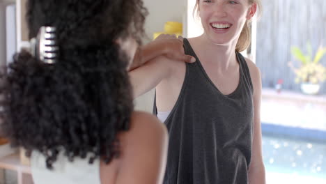 Happy-diverse-fitness-women-exercising-together-on-mat-in-white-room,-slow-motion