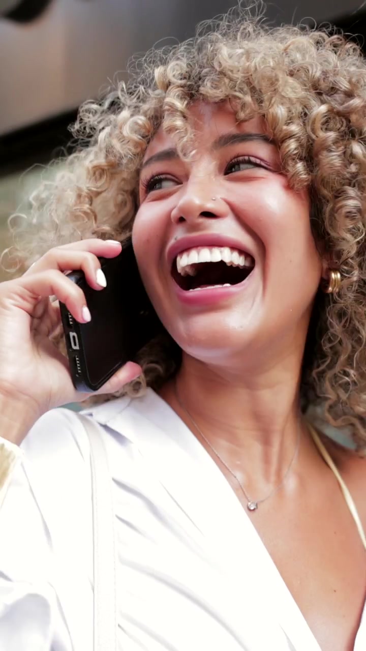 Giovane donna che ride mentre parla al telefono salendo le scale della metropolitana