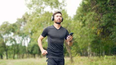 young cheerful active guy sporty running with headphones mobile phone enjoying listening to music
