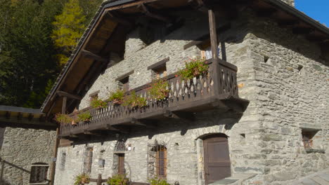 una vista frontal de una casa magnífica y fascinante en courmayeur, mont blanc hecha de piedra con una hermosa cerca de cubo en el valle de aosta, italia