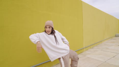 A woman dancing against a yellow wall