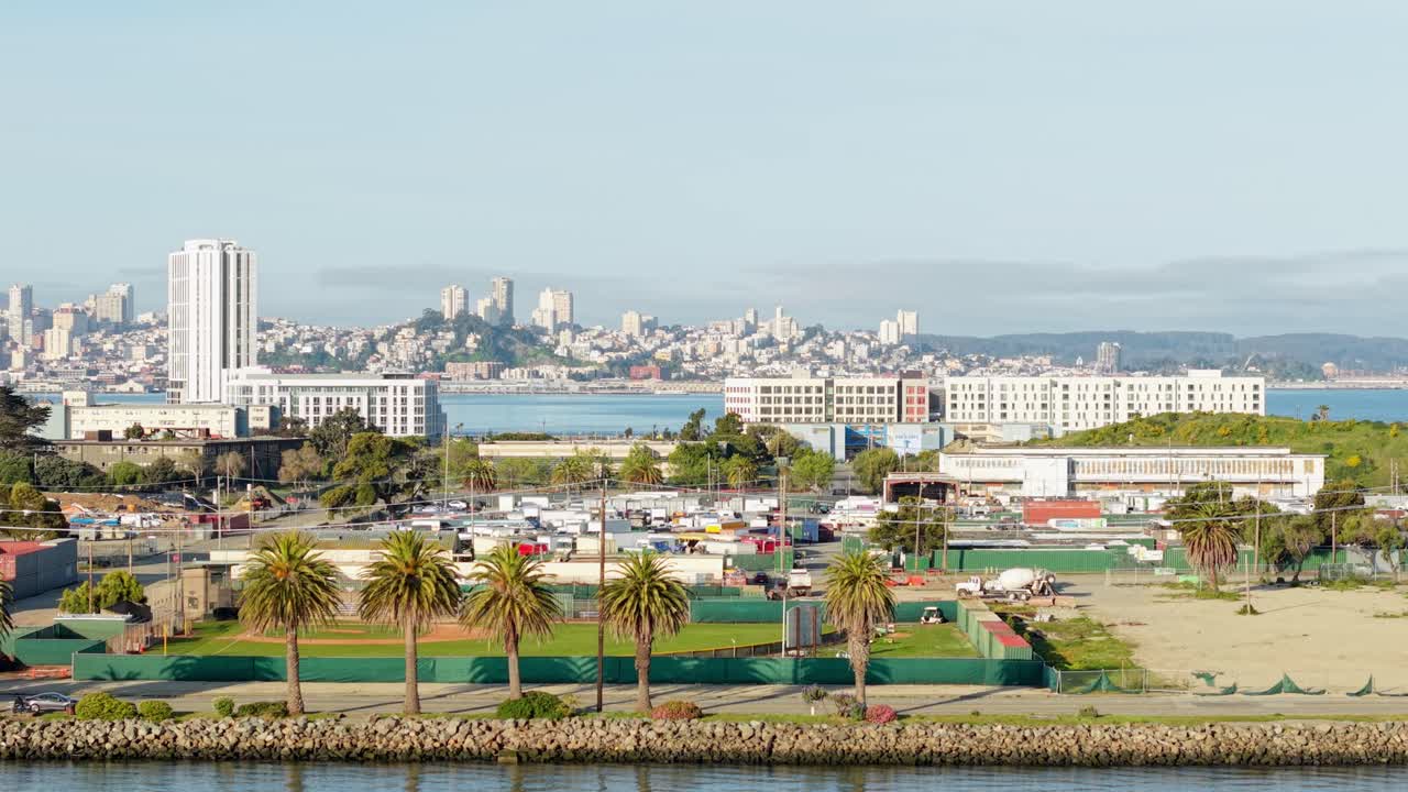 A drone sweeps above Treasure Island, catching glimpses of shipyards, piers, and the glint of the San Francisco skyline.