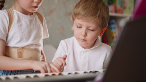Little brother and sister press keys playing music on piano