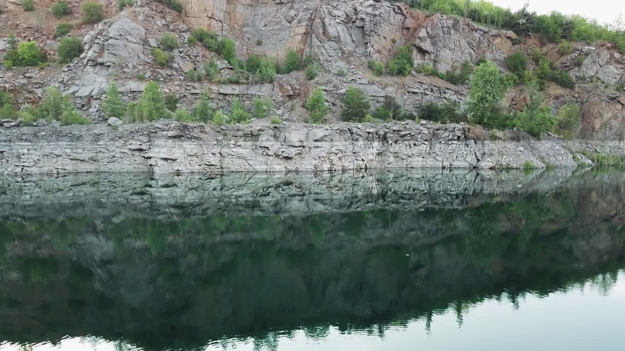 4K aerial video. Smooth takeoff above the water surface. Abandoned quarry, filled with turquoise water.
